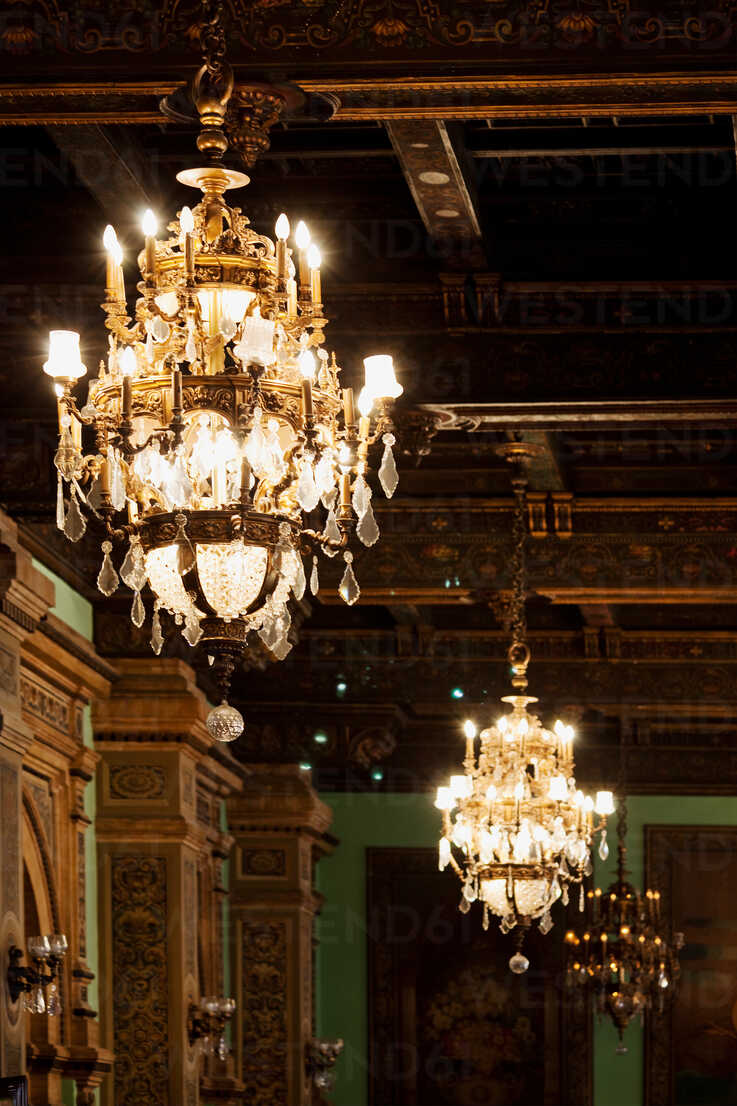 Burning ancient chandeliers hanging on ceiling of museum with patterned pillars and walls